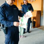 Dzieci wręczaja policjantom podziękowania i papierowe kwiatki