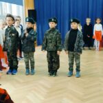 Czworo chłopców ubranych w stroje wojskowe stoi z przodu sceny