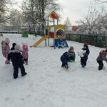 grupa dzieci bawi się na placu zabaw na którym jest śnieg