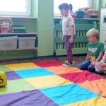 dziewczynka stoi przed kolorowym dywanme