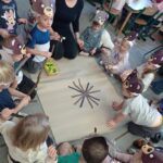 grupa dzieci z nauczycielem wykonuje pracę plastyczną