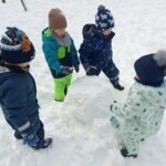 czworo dzieci lepi kulę śnieżną