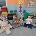 czterech chłopców siedzi na dywanie, trzymają w rękach misie