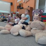 dzieci siedzą na dywanie z misiem