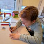 Chłopiec pisze życzenia na kartce