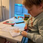 Chłopiec wycina nożyczkami kartkę