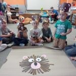 kilkoro dzieci siedzi za misiem wykonanym z pasków