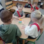 troje dzieci liczy kolorowe patyczki