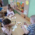 dzieci przy stolikach tworzą obrazki