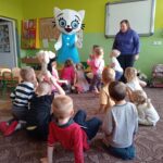 dzieci siedzą na dywanie, pracownik księgarni stoi, obok niego Kicia Kocia