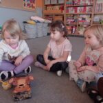 trzy dziewczynki siedzą na dywanie