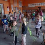 grupa dzieci stoi na dywanie, w ręku wstążki