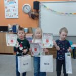 troje dzieci pokazuje dyplomy i prezenty