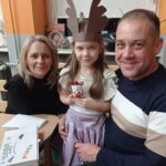 tata, mama i dziewczynka pokazują renifera