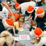 rodzice i dzieci wypełniają na dywanie kartę pracy