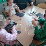 dzieci przy stoliku wycinają elementy pracy