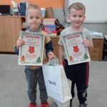 dwóch chłopców trzyma dyplomy