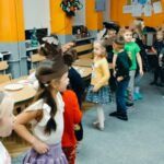 dzieci w opaskach reniferów tańczą na dywanie