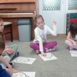 kilkoro dzieci wodzi palcem po obrazku bombki