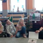 pracownik BWA pokazuje dzieciom obrazki z choinkami