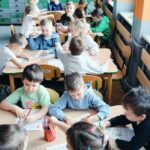 Dzieci uzupełniają karty przy stolikach