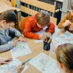 Dzieci przy stolikach kolorują aniołki