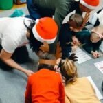 rodzice i dzieci wypełniają na dywanie kartę pracy