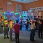 w sali przygaszone światło, dzieci w lęku trzymają światełka