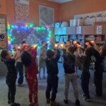 w sali półmrok, dzieci podnoszą światełka do góry