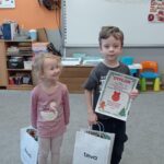 dziewczynka patrzy na chłopca trzymającego dyplom