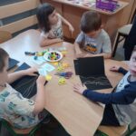 czworo dzieci przy stoliku przewdziewa sznurek