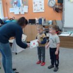 nauczycielka wręcza dyplomy chłopcom