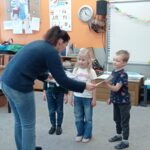 nauczycielka wręcza dzieciom dyplomy