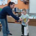 nauczycielka wręcza dyplom chłopcu